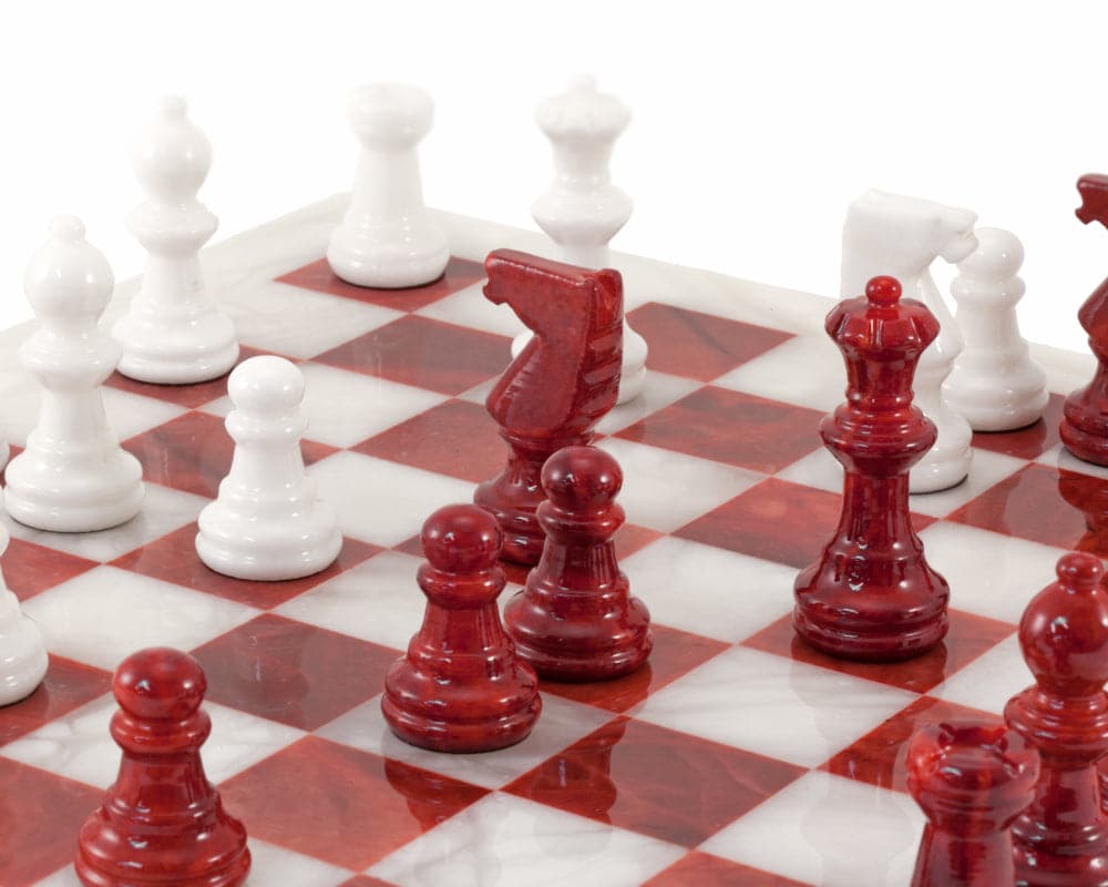 Red and white alabaster chess set with detailed pieces on a polished board, hand made in Italy by Scali Alabastro.