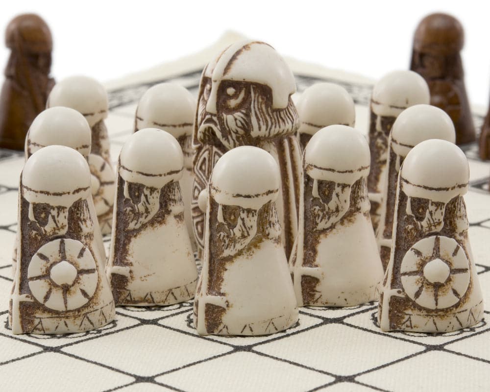 Detailed white and dark pieces for The Viking Game (Hnefatafl) on linen surface showing craftsmanship from National Museum of Scotland