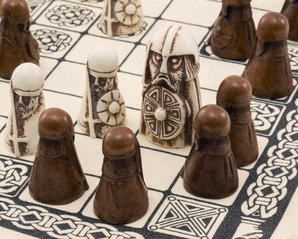 Viking Game Hnefatafl pieces on linen board - white king, defenders, and dark attackers playing a historical strategy game.