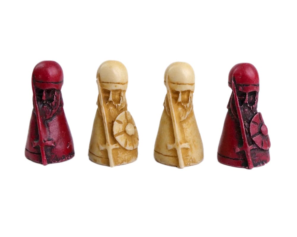 Four intricately carved Hnefatafl game pieces, two red attackers and two white defenders